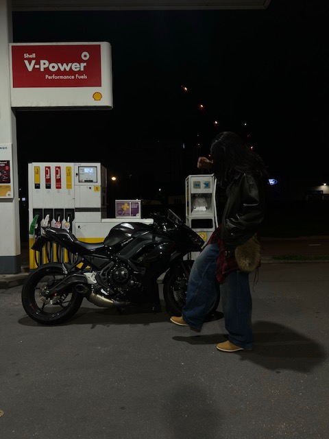 Rider at a late-night fuel stop with a black sportbike