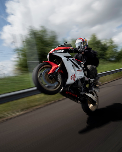 Rider pulling a wheelie on a red and white sportbike